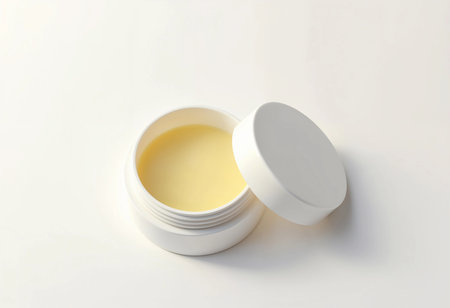 A small white container holds a creamy substance, perfect for skincare routines. The smooth texture shines under soft lighting, suggesting hydration and nourishment for the skin.の素材