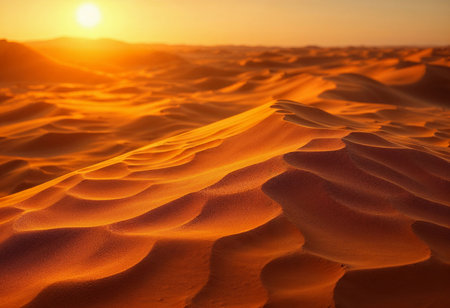 Warm sunlight bathes the undulating dunes of a vast desert landscape, creating a stunning display of golden hues. Shadows dance across the sandy expanse as day transitions to night.の素材