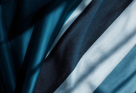 Vibrant shades of teal and navy fabric intertwine, creating a dynamic texture. Soft shadows dance across the material, enhancing its rich colors and inviting touch.の素材