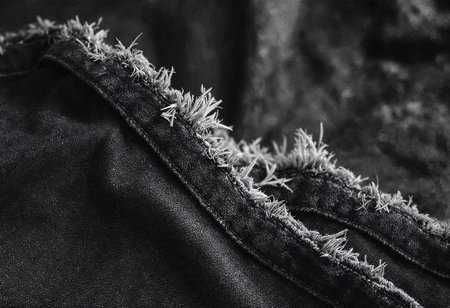 The image captures the fine details of frayed denim, highlighting the contrasting textures and worn edges. This close-up emphasizes the beauty found in the imperfections of fabric.の素材
