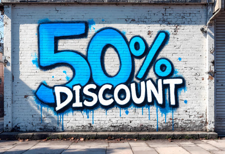 Vibrant graffiti painted on a brick wall showcases a large 50% DISCOUNT in eye-catching blue and white colors, inviting passersby to explore exciting offers in the neighborhood.の素材