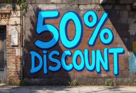 A vibrant mural painted on a brick wall captures attention with its bold blue lettering proclaiming a 50 percent discount. Set against an urban backdrop, it invites passersby to explore.の素材