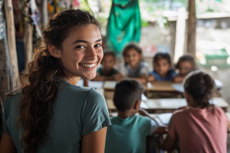 A young girl grins warmly while seated in a lively classroom. Behind her, eager children engage in a learning experience, surrounded by vibrant decorations and a cheerful atmosphere.の素材