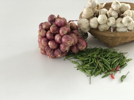 Garlic are in bamboo basket and chilli and onion  are on white background.の写真素材