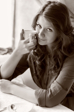A smiling woman in a restaurant is drinking coffeeの写真素材