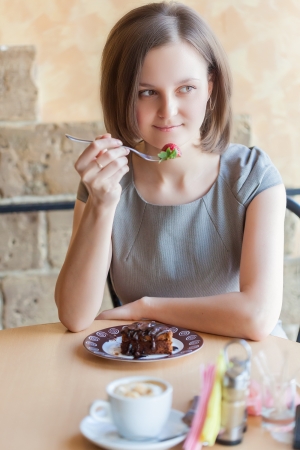 A smiling woman in a restaurant is drinking coffeeの写真素材