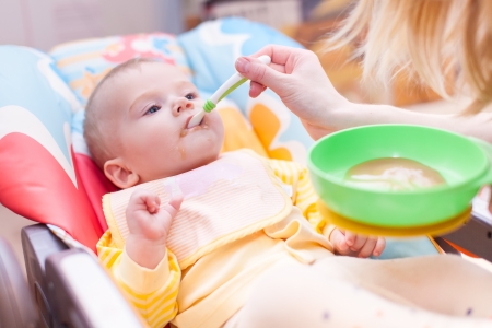 Young blond mother is feeding her babyの写真素材
