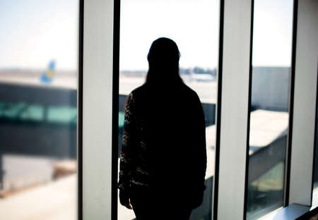 Silhouette of a woman looking at the airport landing groundの写真素材