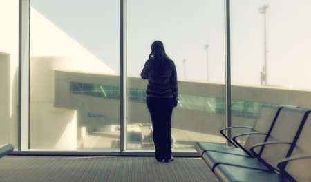 Silhouette of a woman looking at the airport landing groundの写真素材