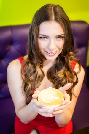 Young teenager girl is drinking coffee in a cafeの写真素材