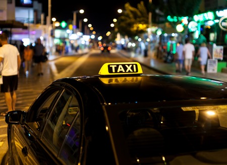 Taxi sign on the roof of a taxi at nightの写真素材