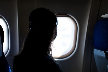 Young woman is looking through a window in the aircraft