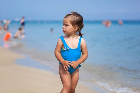 Adorable little girl standing on tropical beach near the seaの写真素材