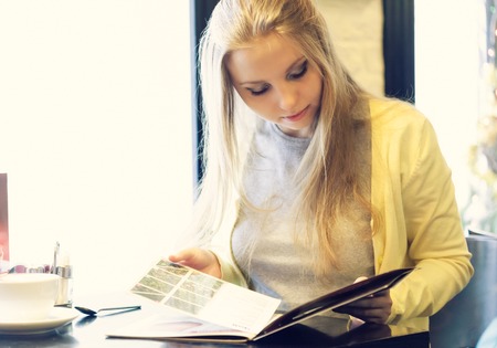 Young woman in a restaurant reading the menu