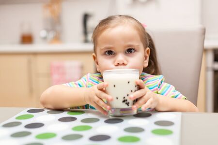 Little girl having breakfast with milk kitchenの写真素材