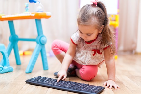 Funny little child playing with computer keyboardの写真素材