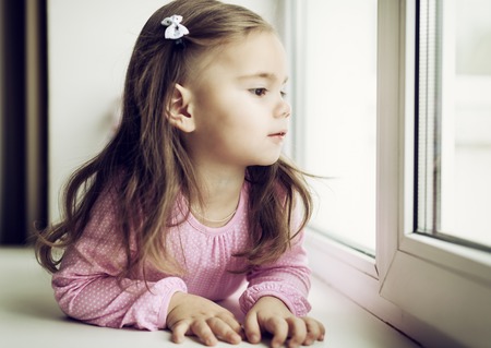 Cute little girl lying on the windowsillの写真素材