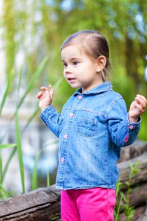 Small girl wearing in denim shirt posing near pondの写真素材