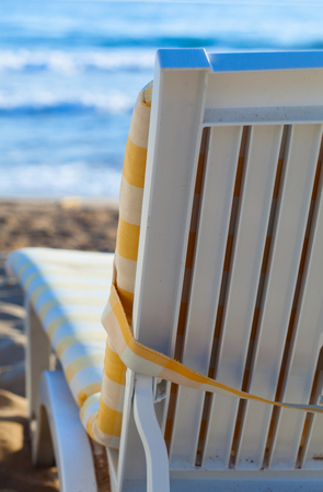 deckchair on sandy beach of blue sea
