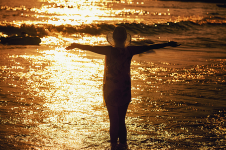 Young woman in summer dress standing in a seaの写真素材