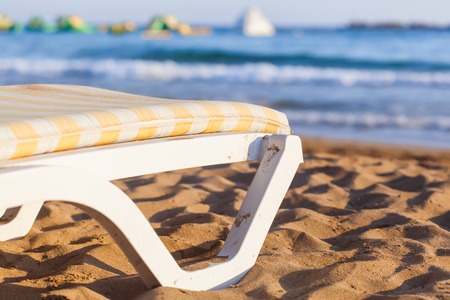 Sun bed on sandy beach of blue sea
