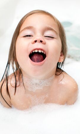 happy little girl is taking a bath with a foam