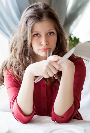 Portrait of hungry woman with fork and knife in handsの写真素材