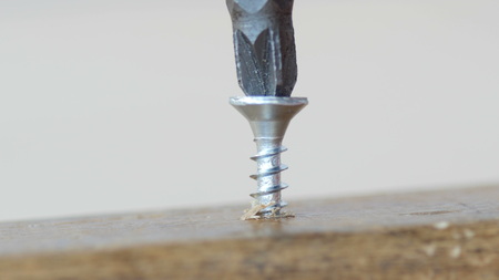 Twisting the screw with a electric screwdriver.
