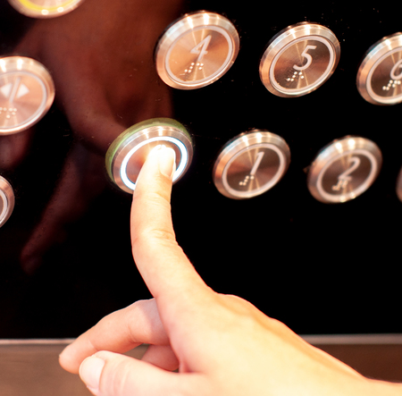 The hand presses on the zero floor elevator buttonの写真素材