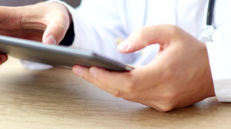 Doctors hands typing prescription on digital tablet