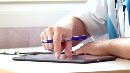 Doctor using a digital tablet and write prescriptionの写真素材