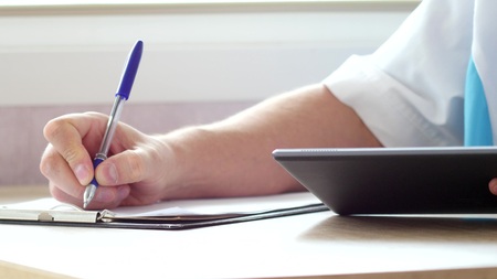 Doctor using a digital tablet and write prescription
