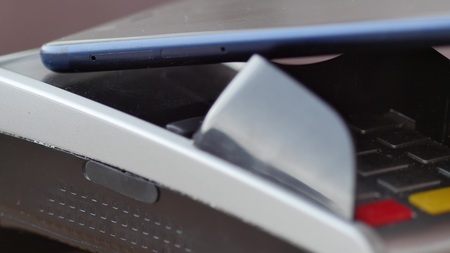 A customer using NFC technology on smartphone to pay by POS terminal.