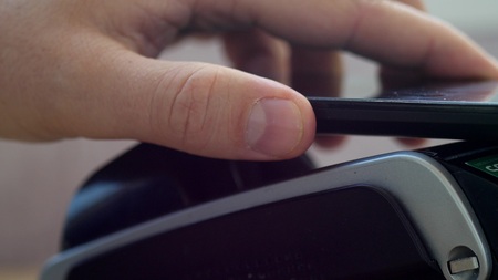 Customer paying with NFC technology by mobile phone on POS terminalの写真素材