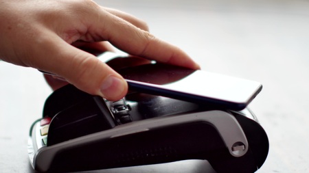 Person using contactless payment with smartphone.