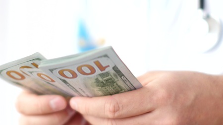 Male doctor counting dollars close-up. Corruption in medicine.