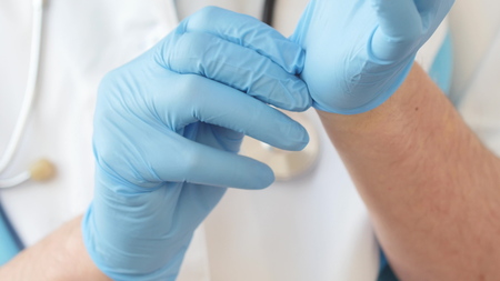 Doctor putting on blue latex gloves