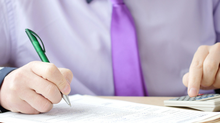 Man filling US tax form or contract. He using a calculatorの写真素材