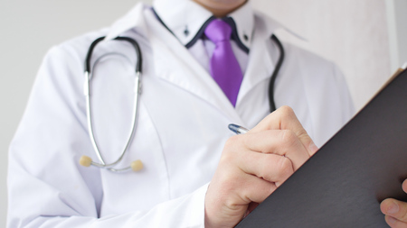 Closeup of male doctor hand writing a medical prescription. A doctor sitting in his cabinetの写真素材