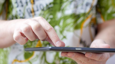 Man hand touching screen on modern digital tablet pc. Close-up image with shallow depth of field. Concept of modern gadgets in useの写真素材