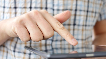 Man hand touching screen on modern digital tablet pc. Close-up image with shallow depth of field. Concept of modern gadgets in useの写真素材