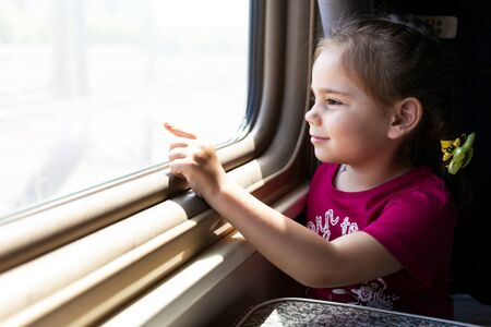 Happy little girl traveling by train.