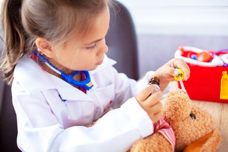 Cute child girl playing doctor with plush toyの写真素材