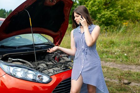 Woman with a broken car on the rural road is calling on mobile phone.の写真素材