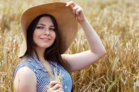 Young beautiful woman resting on golden field of wheatの写真素材