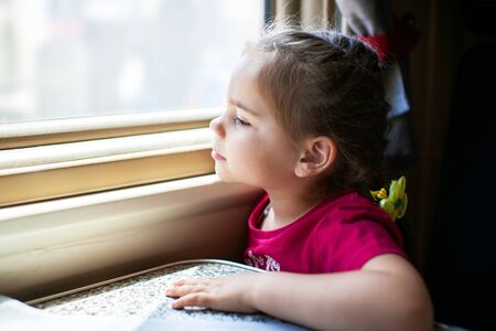 Happy little girl traveling by train.