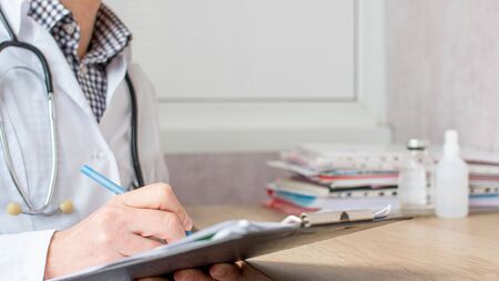 Medical professional doctor writing RX prescription on clipboard
