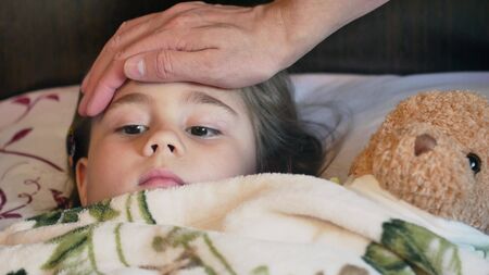 Father putting his hand to the forehead of a childの写真素材