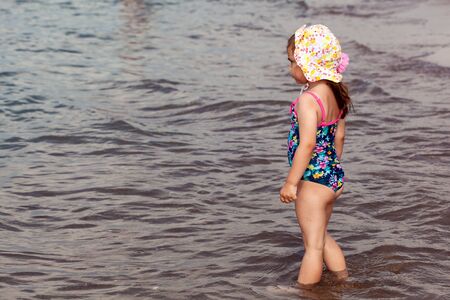 Little child girl on a beach at sunsetの写真素材
