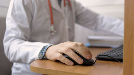 The doctor works at the computer in his office.の写真素材